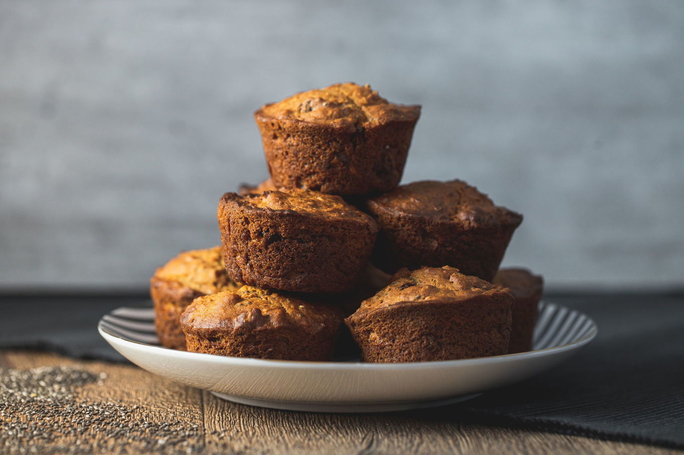 Dozlatova upečené muffiny vyskládané na talíři proti šedému pozadí